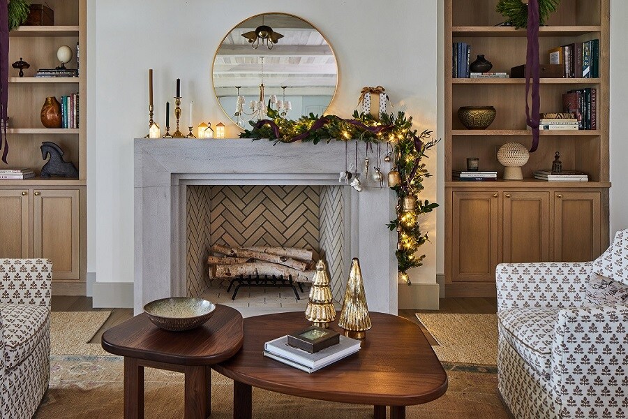 Salon avec cheminée en chevrons, manteau décoré et miroir rond. Décorations de Noël accrochées avec des crochets Command pour une ambiance chaleureuse.
