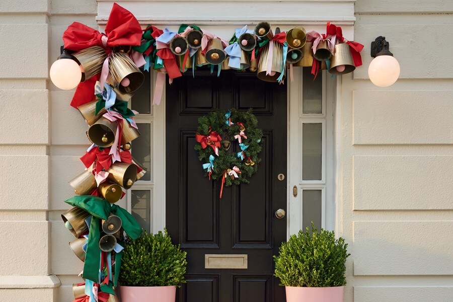 Salon avec cheminée en chevrons, manteau décoré et miroir rond. Décorations de Noël accrochées avec des crochets Command pour une ambiance chaleureuse.
