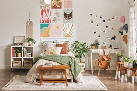 Chambre confortable avec lit bien fait, oreillers et plaid vert. Des œuvres d'art au-dessus du lit avec des bandes Command. Un bureau, une chaise et des photos avec crochets Command ajoutent du charme. Plantes pour la chaleur.
